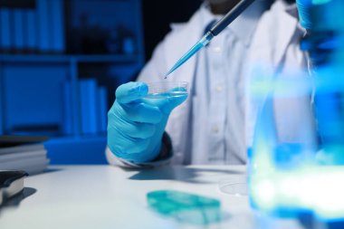 Bir kimyager, laboratuvarında çeşitli bilimsel ekipmanlar kullanarak yeni keşfedilen bir kimyasalı test ediyor..