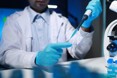 Bir kimyager, laboratuvarında çeşitli bilimsel ekipmanlar kullanarak yeni keşfedilen bir kimyasalı test ediyor..