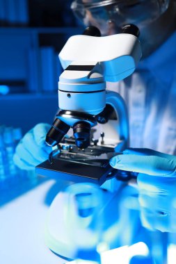 Yetenekli bir bilim adamı laboratuarında mikroskop kullanarak mikroskobik organizmaları mikroskop altında inceler. Araştırmacılar tarafından insanları tedavi etmek için yeni ilaçlar bulmak için kullanılır..