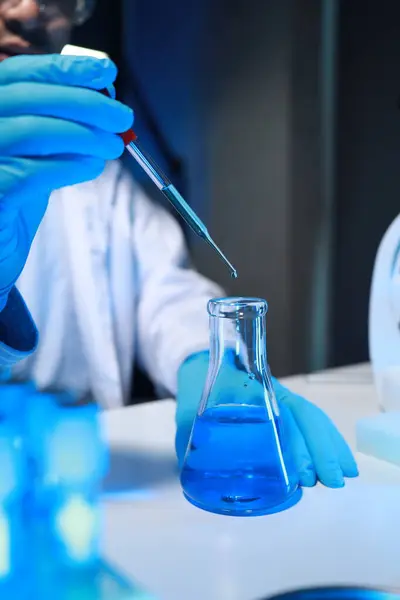 A chemist is testing a newly discovered chemical using a variety of scientific equipment in his lab, The working atmosphere in the laboratory while scientists are doing research.