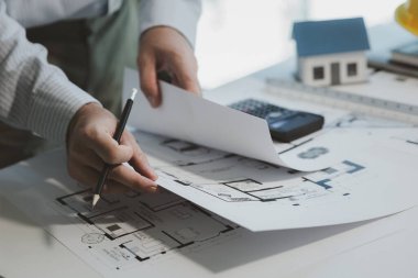 Bir mühendis, yapılacak işi daha iyi anlamak için planları inceliyor, bir mimar, patronunun ona verdiği işi anlamak için özel ofisindeki bina planlarını inceliyor..