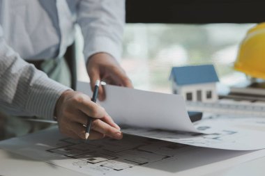 Bir mühendis, yapılacak işi daha iyi anlamak için planları inceliyor, bir mimar, patronunun ona verdiği işi anlamak için özel ofisindeki bina planlarını inceliyor..
