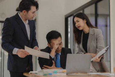 Bir grup çalışan stresle birlikte çalışıyor çünkü bu iş, patronun onlara teslim olmalarını söylediği süreyi aştı. Çalışanlar çalışırken stres yaptı çünkü iş çok fazlaydı..