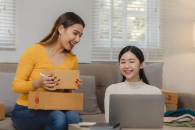 İki işletme sahibi alıcıya teslim edilmeden önce müşteri bilgilerini kontrol ediyor, iki iş arkadaşı sipariş verilerinin satış rakamlarıyla eşleştiğini kontrol ediyor.