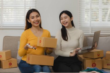 İki işletme sahibi alıcıya teslim edilmeden önce müşteri bilgilerini kontrol ediyor, iki iş arkadaşı sipariş verilerinin satış rakamlarıyla eşleştiğini kontrol ediyor.