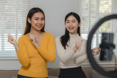 İki güzel Asyalı kadın kendilerini eğlendirmek için elektronik aletler kullanıyorlar. Dairelerinde dans ediyorlar ve hafta sonları evde mutlu bir şekilde vakit geçiriyorlar..