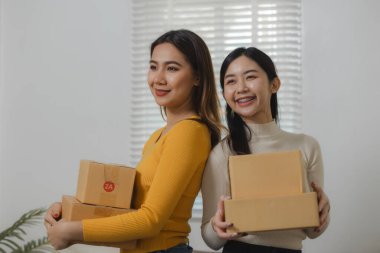 İki çevrimiçi satıcı ellerinde kutular dolusu ürün tutuyordu, iki operatör, ürünleri mağazadan satın alan müşterilere teslim etmek için paket hazırlıyordu..