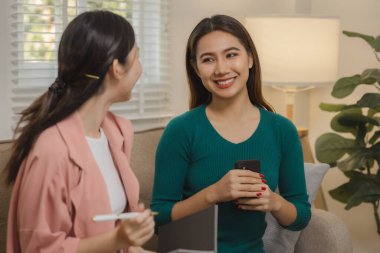 İki güzel Asyalı kadın kendilerini dairelerinde grup aktivitesi olarak eğlendirmek için elektronik cihazlar kullanıyorlar hafta sonları evlerindeki kanepede birlikte vakit geçiriyorlar..