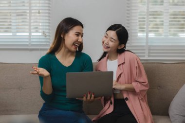 Güzel bir Asyalı kadın yurtdışındaki arkadaşlarıyla konuşmak için bir iletişim cihazı kullanıyor, evdeki kanepede dinleniyor ve kendi eğlence aktivitelerini yapıyor..