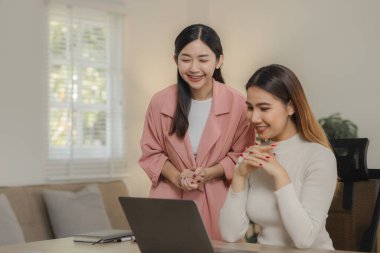 Asyalı kadın çalışanlar evde çalışıyor çünkü salgın nedeniyle önemli bir toplantıları var, iki iş kadını evlerinde birlikte çalışıyor ve eğleniyorlar..
