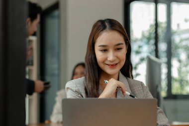 bir çalışan modern ofiste çalışıyor ve diğer iş arkadaşları aynı odada, ofiste çalışıyor, iş adamları, şirkette mutlu bir şekilde çalışıyorlar.