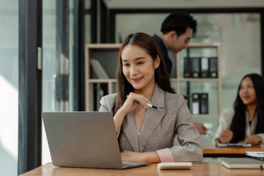 bir çalışan modern ofiste çalışıyor ve diğer iş arkadaşları aynı odada, ofiste çalışıyor, iş adamları, şirkette mutlu bir şekilde çalışıyorlar.