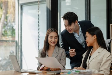 Bir grup iş adamı modern ofiste beyin fırtınası yapıyor, bir fikri paylaşmak için takım çalışması yapıyorlar, proje için kullanacakları strateji hakkında konuşuyorlar.