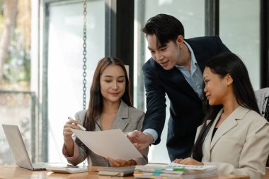 Bir grup iş adamı modern ofiste beyin fırtınası yapıyor, bir fikri paylaşmak için takım çalışması yapıyorlar, proje için kullanacakları strateji hakkında konuşuyorlar.