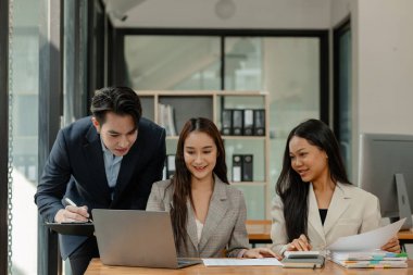 Bir grup iş adamı modern ofiste beyin fırtınası yapıyor, bir fikri paylaşmak için takım çalışması yapıyorlar, proje için kullanacakları strateji hakkında konuşuyorlar.