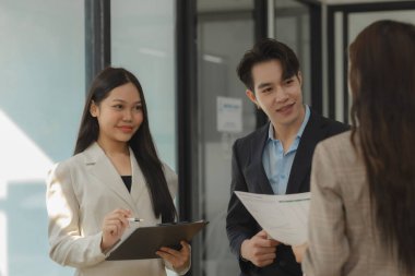 Bir grup iş adamı modern ofiste beyin fırtınası yapıyor, bir fikri paylaşmak için takım çalışması yapıyorlar, proje için kullanacakları strateji hakkında konuşuyorlar.