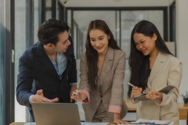 Bir grup iş adamı modern ofiste beyin fırtınası yapıyor, bir fikri paylaşmak için takım çalışması yapıyorlar, proje için kullanacakları strateji hakkında konuşuyorlar.