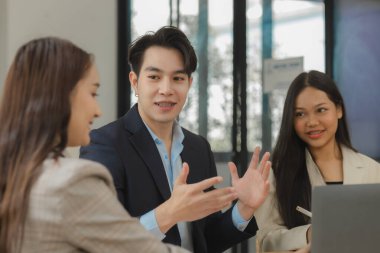 Bir grup iş adamı modern ofiste beyin fırtınası yapıyor, bir fikri paylaşmak için takım çalışması yapıyorlar, proje için kullanacakları strateji hakkında konuşuyorlar.