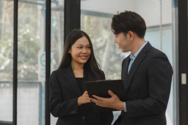 İki çalışan toplantı raporu hakkında konuşuyor. Meslektaşlar birbirleriyle tartışıyor ve tavsiyelerde bulunuyorlar. Mutlu çalışma ortamı, birlikte çalışma..