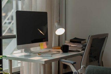 Ofis içinde masası olan bir atmosfer, insanların olmadığı bir işyeri, bilgisayar monitörü ve masadaki bir yığın belge, ofis malzemesi dışında boş bir oda.