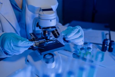 Bilimadamı laboratuvarda mikroskop kullanıyor, kimyasal araştırmacı kimya üzerine yoğunlaşarak çalışıyor, kimyager deneysel maddeleri test etmek için mikroskop kullanarak bir bilim deneyi yürütüyor.