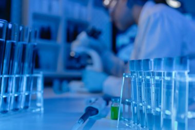 Bilimadamı laboratuvarda mikroskop kullanıyor, kimyasal araştırmacı kimya üzerine yoğunlaşarak çalışıyor, kimyager deneysel maddeleri test etmek için mikroskop kullanarak bir bilim deneyi yürütüyor.