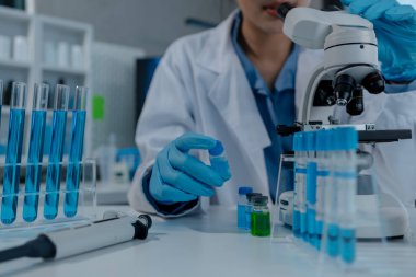 Bilimadamı laboratuvarda mikroskop kullanıyor, kimyasal araştırmacı kimya üzerine yoğunlaşarak çalışıyor, kimyager deneysel maddeleri test etmek için mikroskop kullanarak bir bilim deneyi yürütüyor.