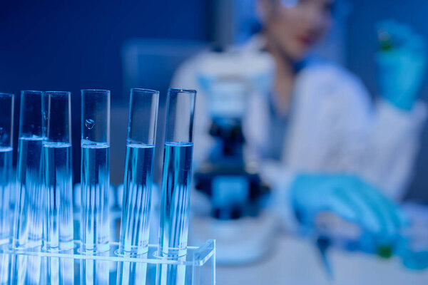 учёный работает над важной жидкостью внутри трубки в лаборатории, было обнаружено открытие вакцины для защиты от распространяющегося вируса, носить перчатки и очки для безопасности