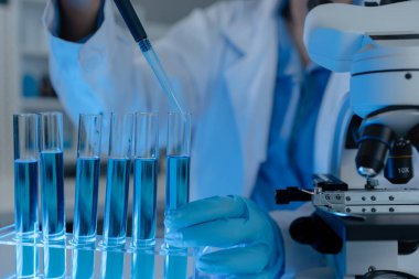 Bilim adamı laboratuvarda önemli bir sıvı üzerinde çalışıyor. Virüsün yayılmasına karşı korunacak bir aşı bulundu. Güvenlik için eldiven ve gözlük takın.