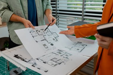 Bir mimar ve mühendis takım olarak çalışır, bir mühendis iş arkadaşıyla ev modelinin detaylarını tartışır. Aynı olduğundan emin olmak için planlarla karşılaştırır.