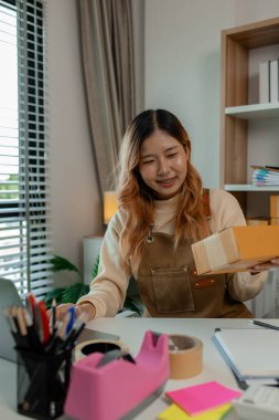 İşyeri sahibinin iş yerinde kontrol listesi var, müşterilere teslim edilmeden önce tüm paketler hakkında iyi hazırlıklar yapıyor, müşteri bilgilerini doğruluğu için kontrol ediyor.