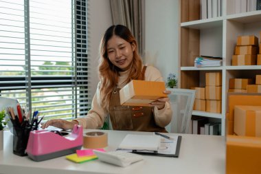 İşyeri sahibinin iş yerinde kontrol listesi var, müşterilere teslim edilmeden önce tüm paketler hakkında iyi hazırlıklar yapıyor, müşteri bilgilerini doğruluğu için kontrol ediyor.