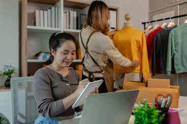 Bir girişimci, çalışanlarının giysi ürünlerini mağazadan müşterilere teslim etmek için hazır hale getirmek için çalıştıkları mağazadaki malları incelemeye geldi.