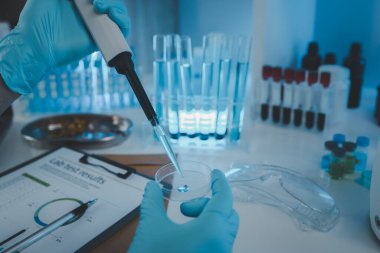 Bir araştırmacı sıvı madde üzerinde bilimsel deneyler yapıyor, bir bilim adamı sıvı örneğini analiz etmek için laboratuvar ekipmanları kullanıyor, kimyasallar laboratuarda test ediliyor.