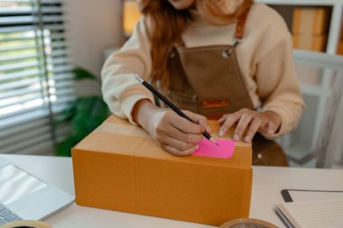 Güzel bir bayan çalışan, giysi parçalarını paket kutusuna koyuyor. Uygun prosedürleri izleyip, müşterinin siparişine ulaştırmak için, güçlü ambalajlar hazırlıyor.