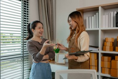 Bir girişimci, çalışanlarının giysi ürünlerini mağazadan müşterilere teslim etmek için hazır hale getirmek için çalıştıkları mağazadaki malları incelemeye geldi.