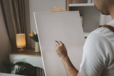 Bir sanatçı kendi resim stüdyosunda tuval, palet, suluboya, yağlar, poster renkleri, sanatsal, ressam, renkler, yaratıcılık, beceri gibi çeşitli resim aletleriyle oturuyor.