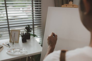 Bir sanatçı kendi resim stüdyosunda tuval, palet, suluboya, yağlar, poster renkleri, sanatsal, ressam, renkler, yaratıcılık, beceri gibi çeşitli resim aletleriyle oturuyor.