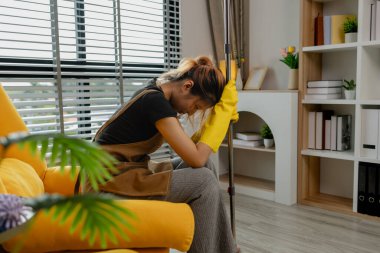 Bütün gün evi temizledikten sonra yorgun hissediyor ve yerdeki koltuğa oturuyor. Sabahtan öğlene kadar bir sürü ev işi yaptı. Dinlenmeye ihtiyacı var.