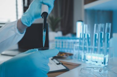 Bir araştırmacı sıvı madde üzerinde bilimsel deneyler yapıyor, bir bilim adamı sıvı örneğini analiz etmek için laboratuvar ekipmanları kullanıyor, kimyasallar laboratuarda test ediliyor.