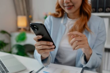 Bir iş kadını gün içinde boş zamanlarında ofisinde dinlenirken, genç bir bayan çalışanı ofisinde mutlu bir şekilde gülümsüyor çünkü tüm işlerini temizlemeyi bitirmiş.
