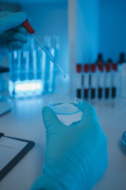 Bir araştırmacı sıvı madde üzerinde bilimsel deneyler yapıyor, bir bilim adamı sıvı örneğini analiz etmek için laboratuvar ekipmanları kullanıyor, kimyasallar laboratuarda test ediliyor.