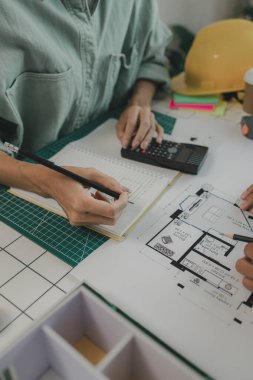 Bir mimar ve asistanı beyin fırtınası yapıyor ve planları inceliyor, iki mühendis yapıyı güçlendirmek, taslak, toplantı, takım çalışması yapmak için bir inşaat planını tartışıyorlar.