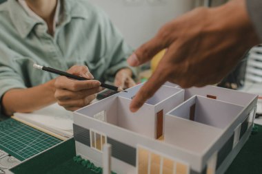 Mühendis ve yatırımcı, yakında inşa edilecek bir konut projesinin detaylarını görüşüyorlar. Bir mimar, müşterinin ihtiyaçlarını karşılayacak bir ev yapısı tasarlamak için bir mühendise danışıyor.