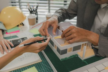 Mühendis ve yatırımcı, yakında inşa edilecek bir konut projesinin detaylarını görüşüyorlar. Bir mimar, müşterinin ihtiyaçlarını karşılayacak bir ev yapısı tasarlamak için bir mühendise danışıyor.