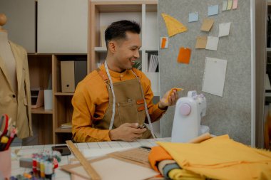 Moda tasarımcısı atölyesinde çalışıyor. Sevdiği şeyleri yapıyor. Bir elbise dikmek için dikiş makinesi kullanmak, elbiseyi dikmek için kumaşı seçmek gibi.
