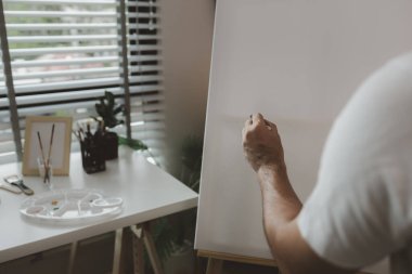 Bir sanatçı kendi resim stüdyosunda tuval, palet, suluboya, yağlar, poster renkleri, sanatsal, ressam, renkler, yaratıcılık, beceri gibi çeşitli resim aletleriyle oturuyor.