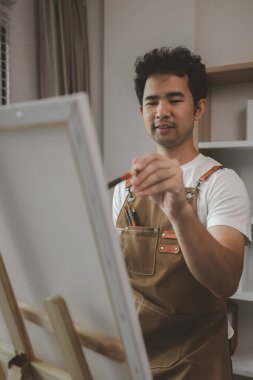 Bir sanatçı kendi resim stüdyosunda tuval, palet, suluboya, yağlar, poster renkleri, sanatsal, ressam, renkler, yaratıcılık, beceri gibi çeşitli resim aletleriyle oturuyor.