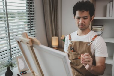 Bir sanatçı kendi resim stüdyosunda tuval, palet, suluboya, yağlar, poster renkleri, sanatsal, ressam, renkler, yaratıcılık, beceri gibi çeşitli resim aletleriyle oturuyor.