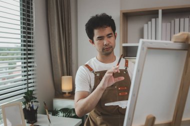 Bir ressam resim stüdyosunda, yükselen bir erkek sanatçı hem resim, palet, tuval, boya, yağlı boya boya, poster renkleri gibi en iyi tablolarını yapmaya odaklanıyor..